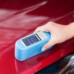 Technician measuring gloss on an automotive plastic panel with a handheld glossmeter at GPTesting in Harper Woods, Michigan