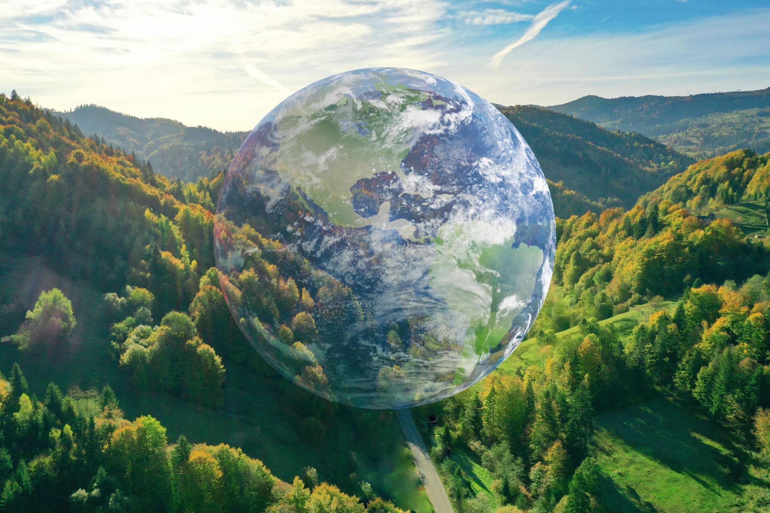 Globe of the world in a natural environment with trees and grass on hills under the daytime sky